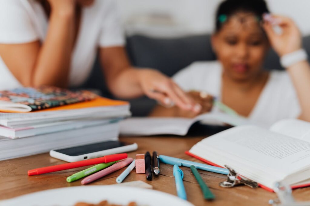 pexels-photo-5311395-1 A mother and child studying with books and stationery at a wooden table.