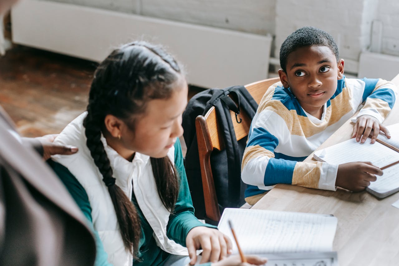 Diverse students attentively studying and writing in an indoor classroom setting.