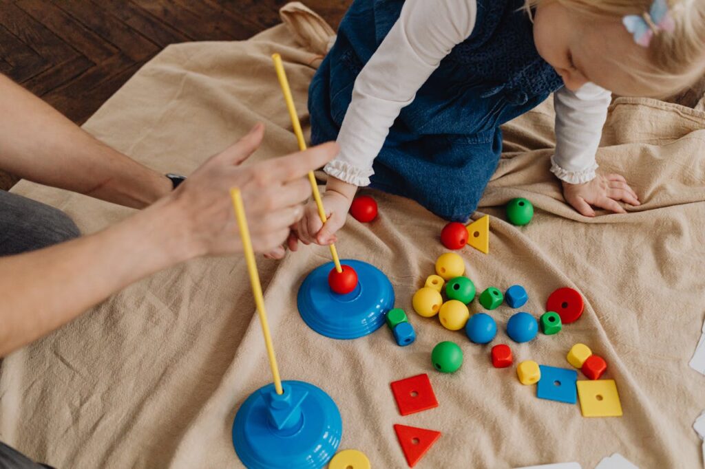 pexels-photo-7296459 A child playing with educational toys, learning shapes and colors with a supervising adult.